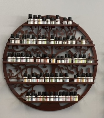 Round tree of life wall rack filled with rows of essential oil bottles at SereniTea Boutique