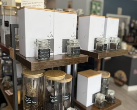 Tea display shelf with Session Longjing and Jasmine Bai Hao jars plus decaf canisters at SereniTea Boutique in Lee's Summit