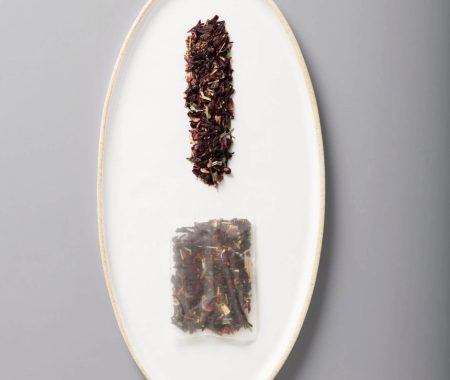 Hibiscus and lemongrass iced tea blend shown loose and in a large brewing sachet at SereniTea Boutique