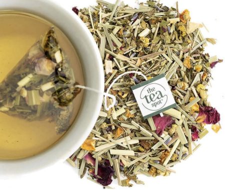 Herbal tea sachet steeping in a cup beside a loose blend of lemongrass, chamomile, and rose petals at SereniTea Boutique