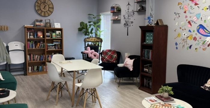 The Book Nook lounge at SereniTea Boutique with bookshelves, cozy chairs, tables, and Once Upon a Time lettering on the wall