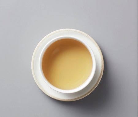 Pale golden brewed white tea in a white ceramic cup and saucer at SereniTea Boutique